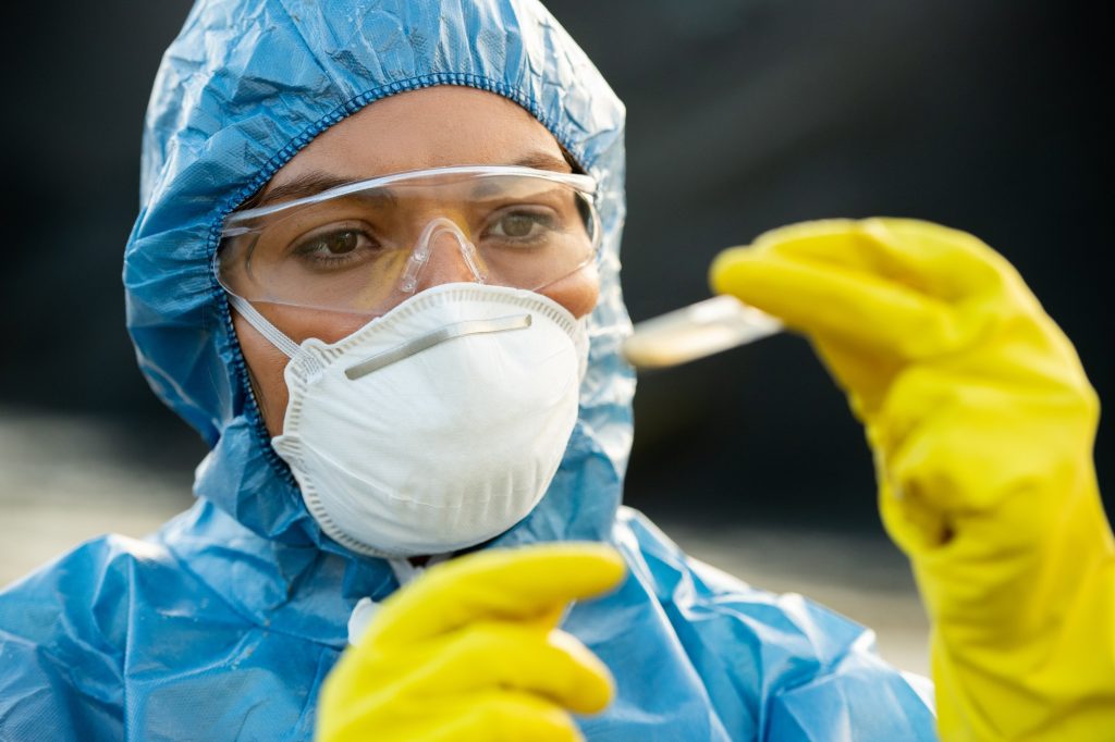 Young researcher in protective workwear looking at sample of toxic soil or water